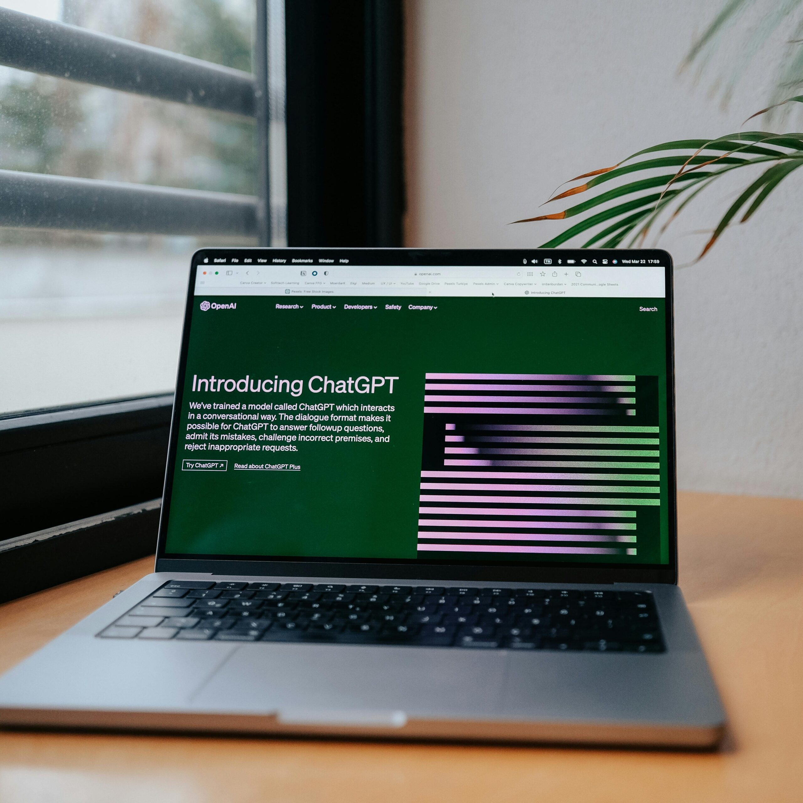 A laptop displaying ChatGPT on a desk by a window, featuring a modern home office setup.